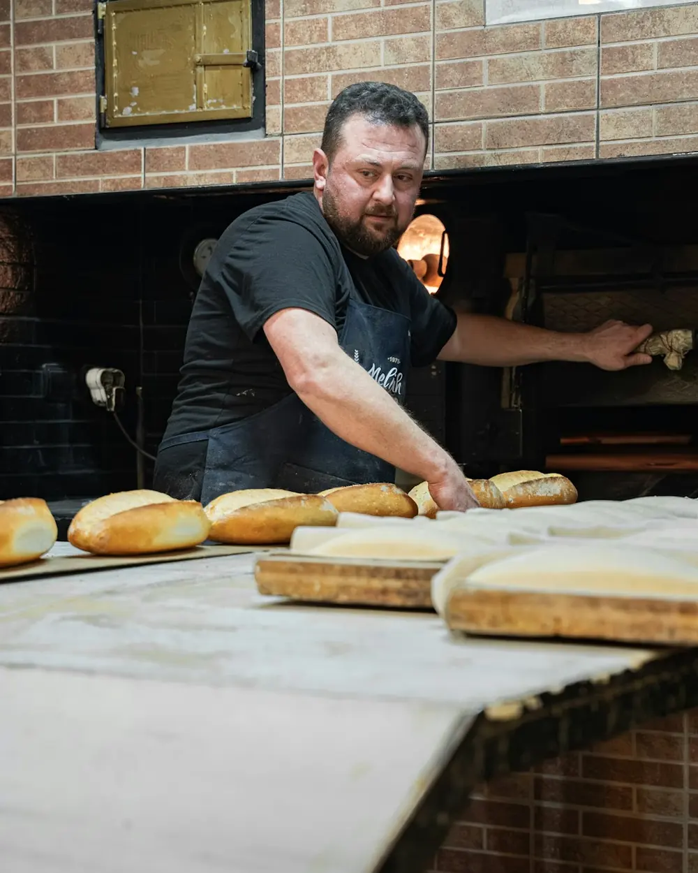 Pembuat roti di depan oven kayu