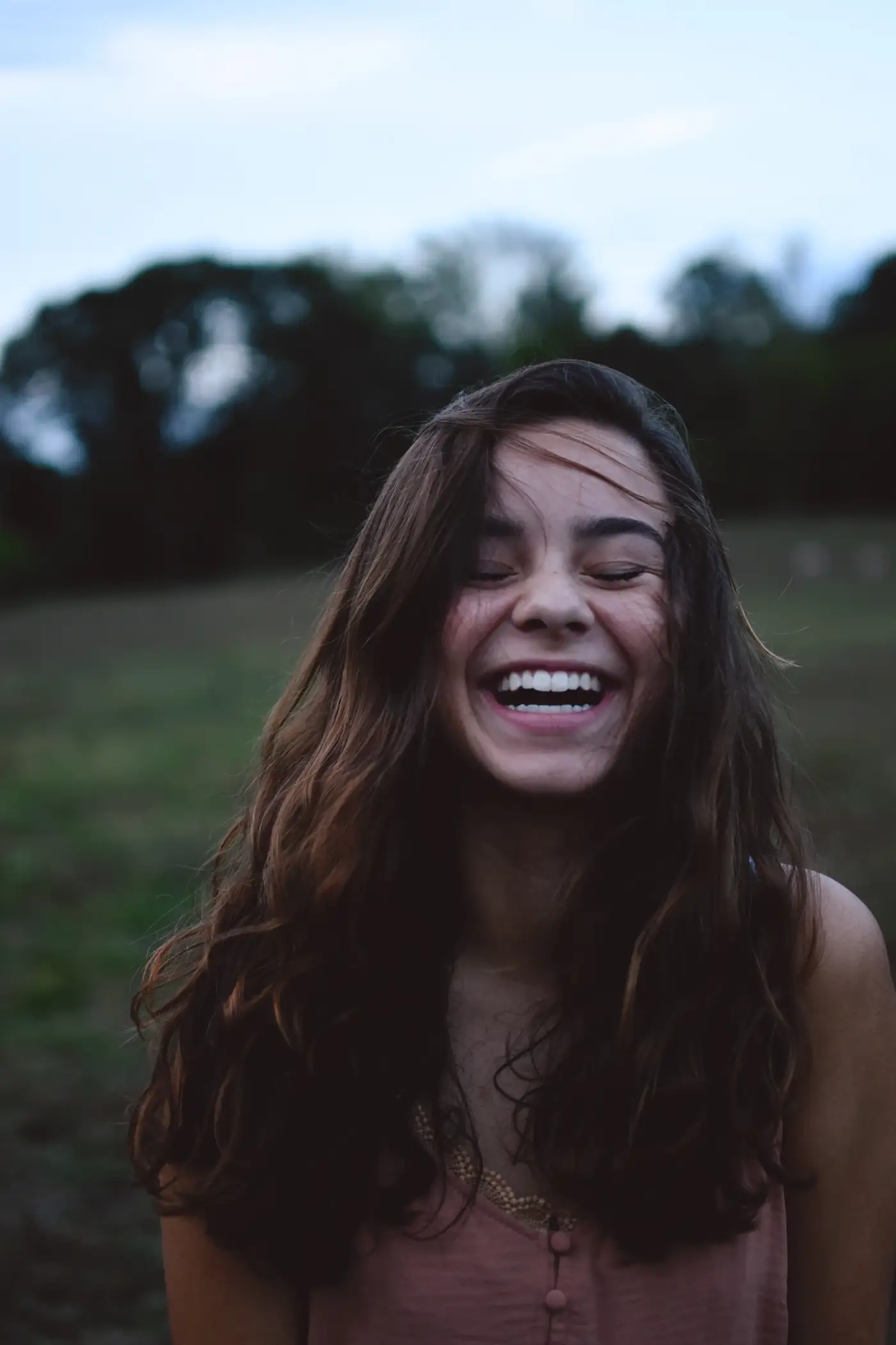 Woman laughing outdoors at dusk
