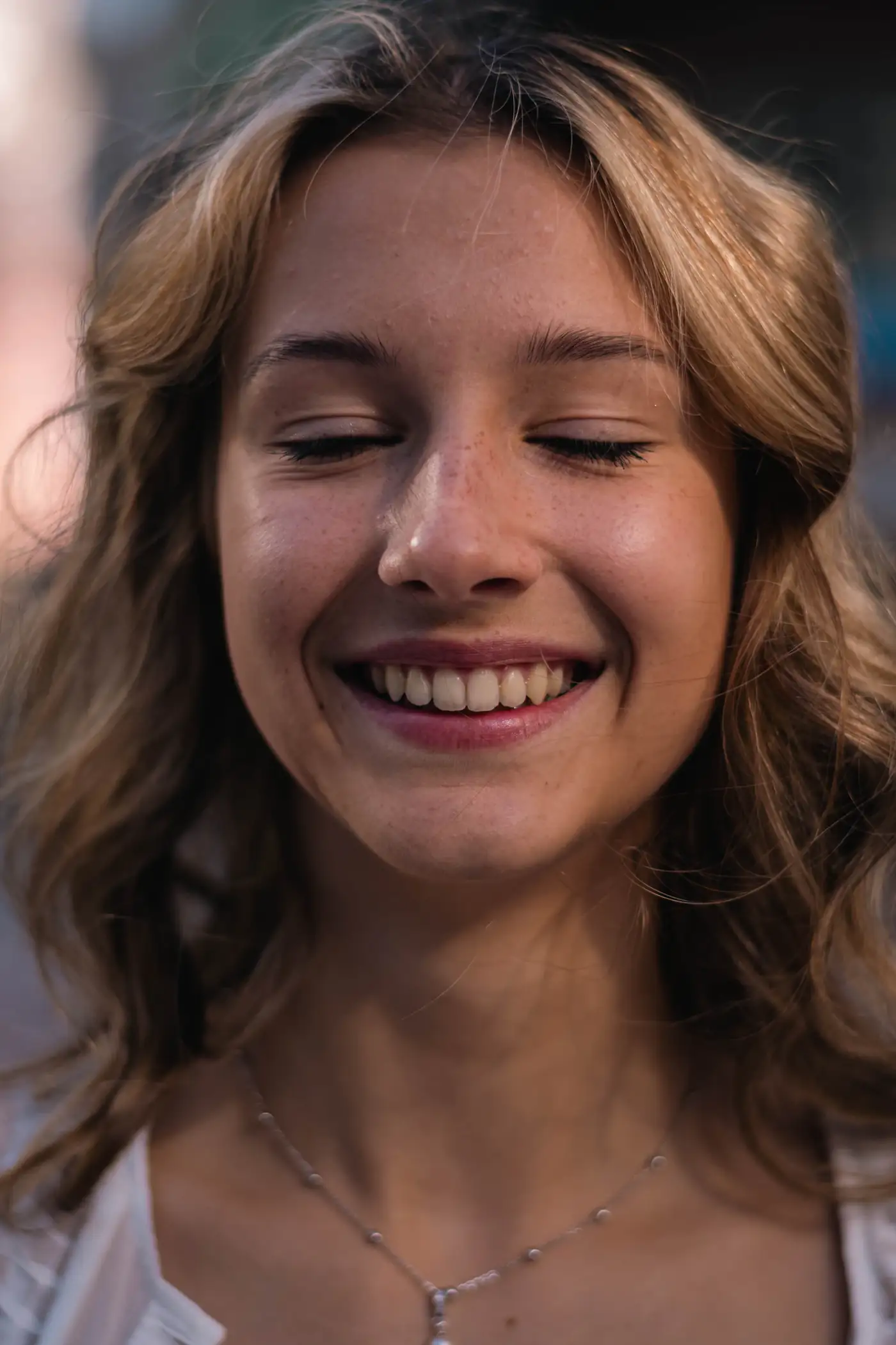 Woman with freckles smiling with her eyes closed