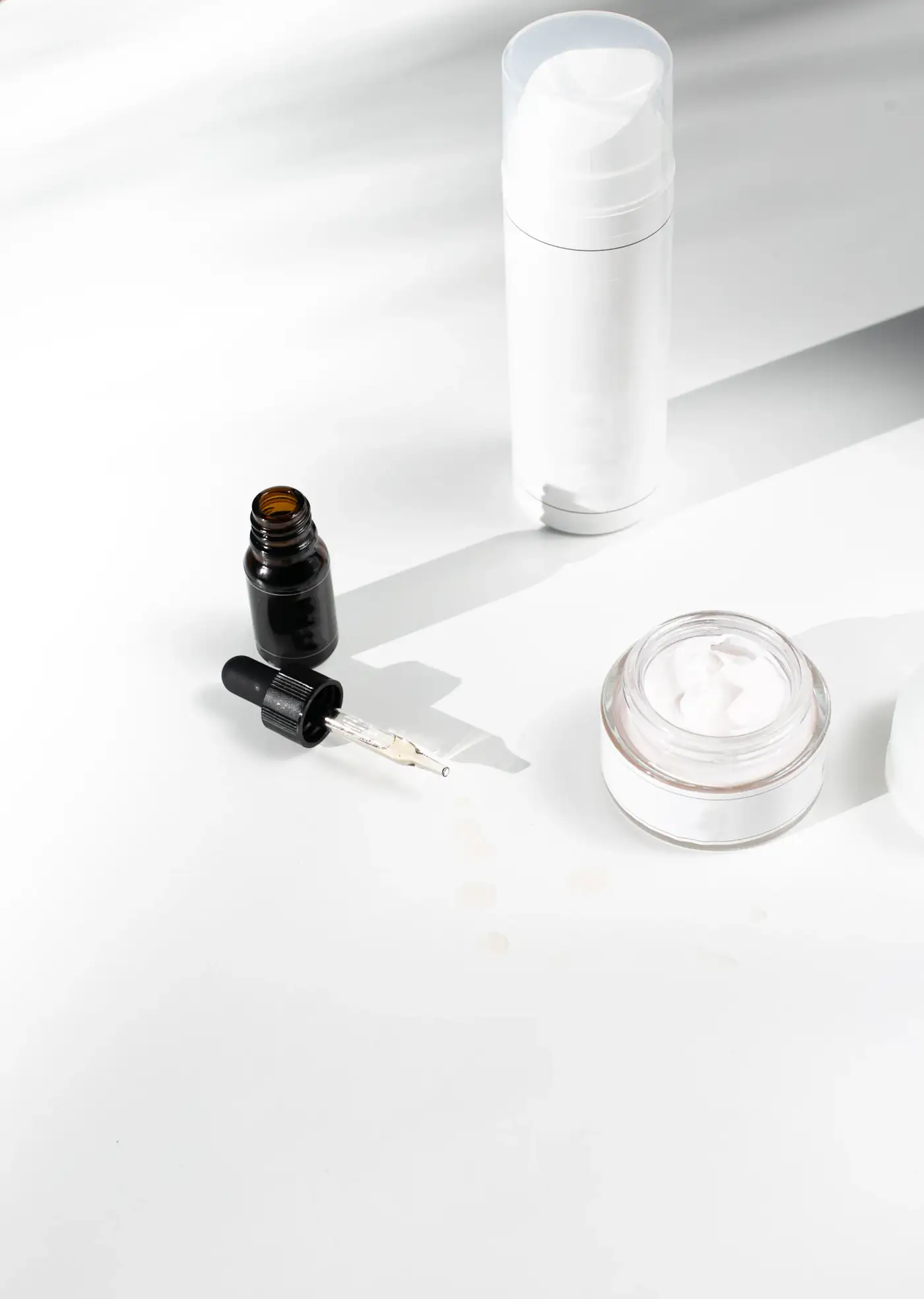 White dropper bottle and a jar of cream