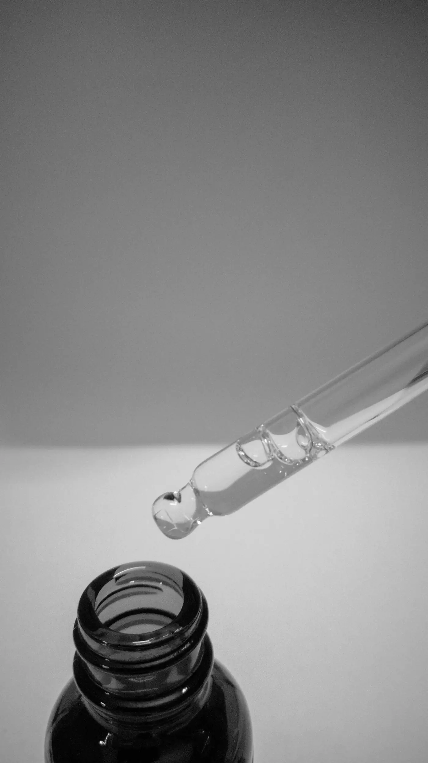Pipette releasing a drop in black and white