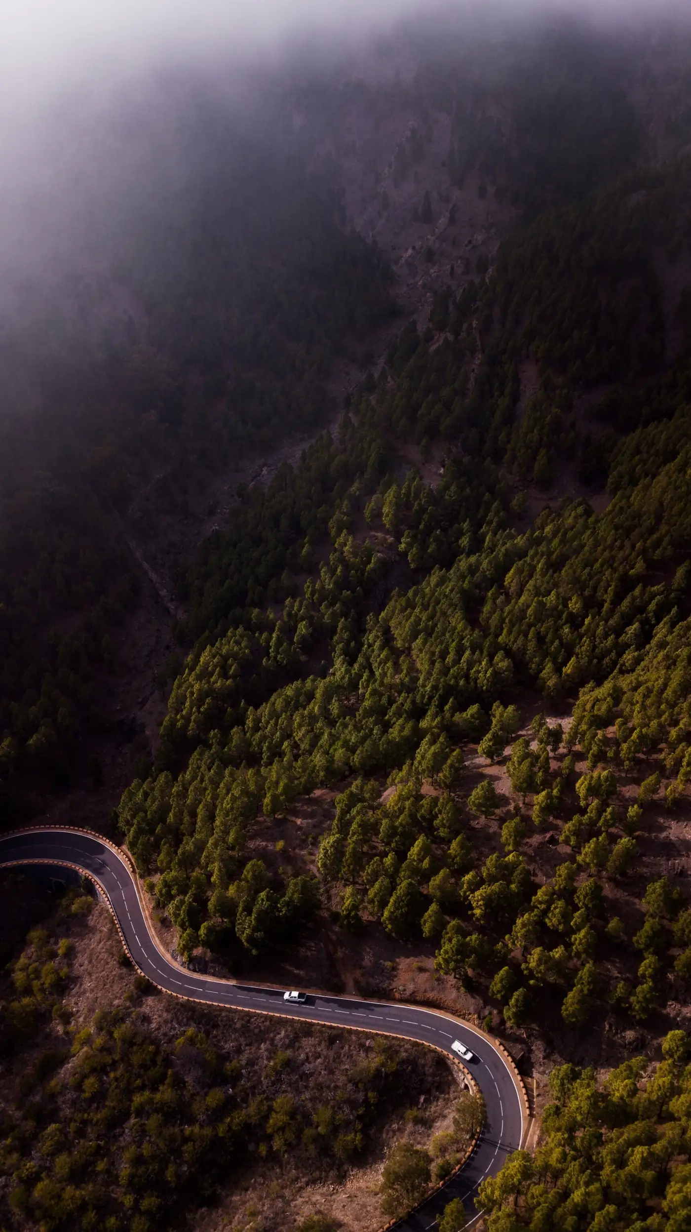Aerial view of a road through dark green hills
