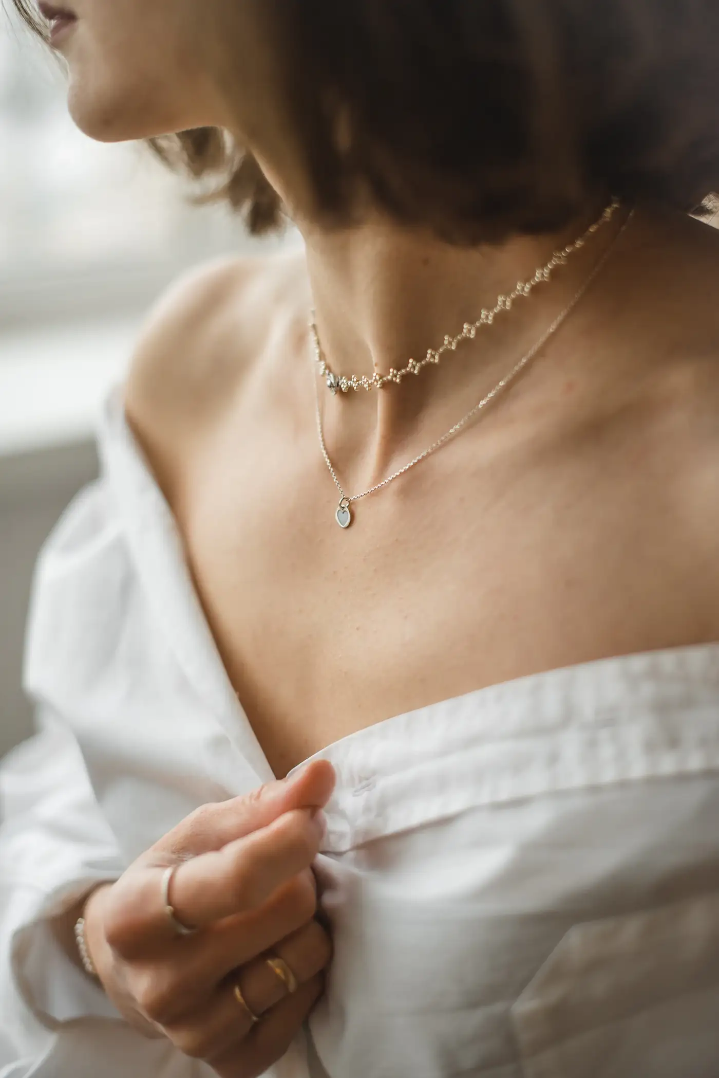 Delicate gold necklaces on a collarbone with a white shirt