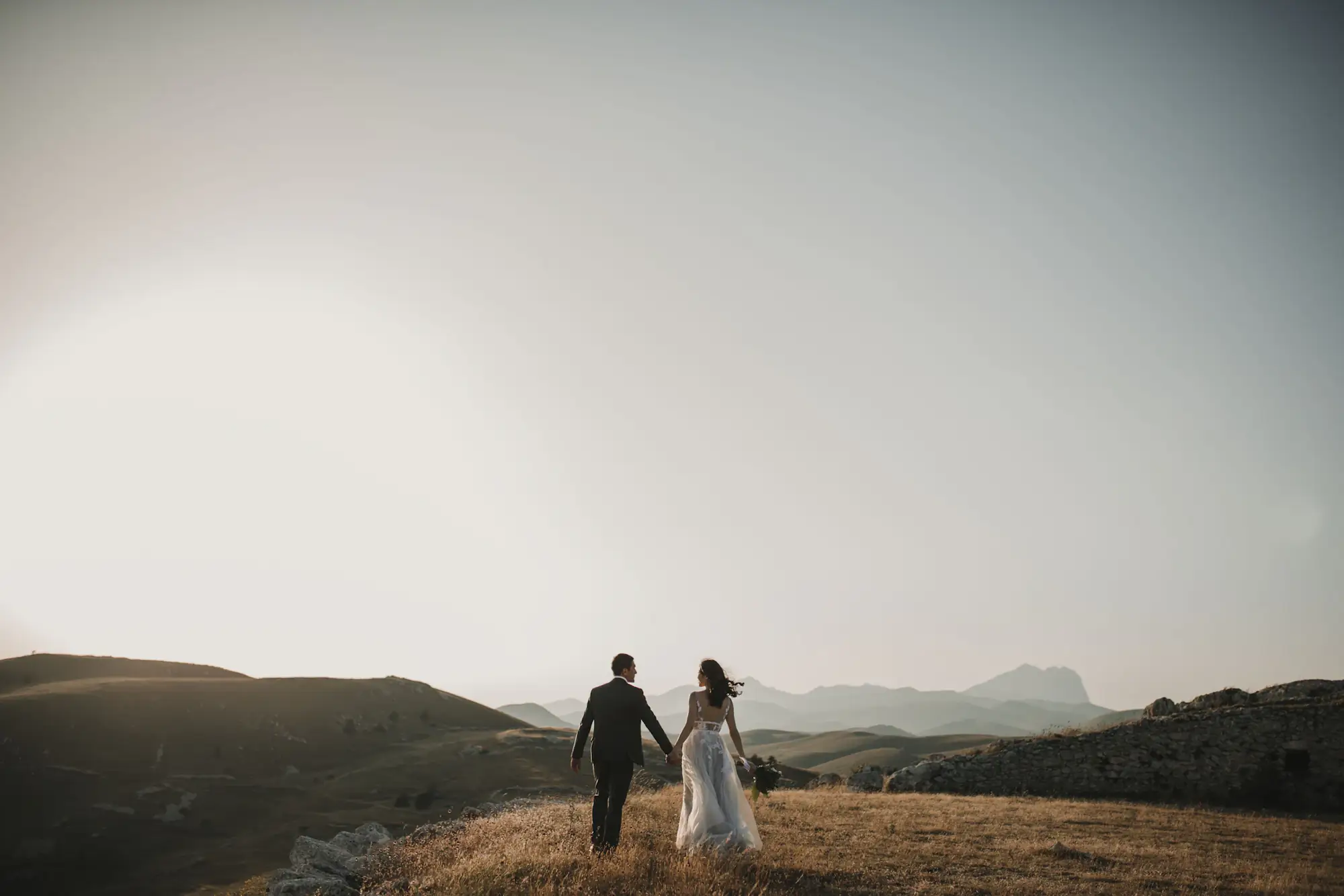 Couple walking hand in hand across misty hills