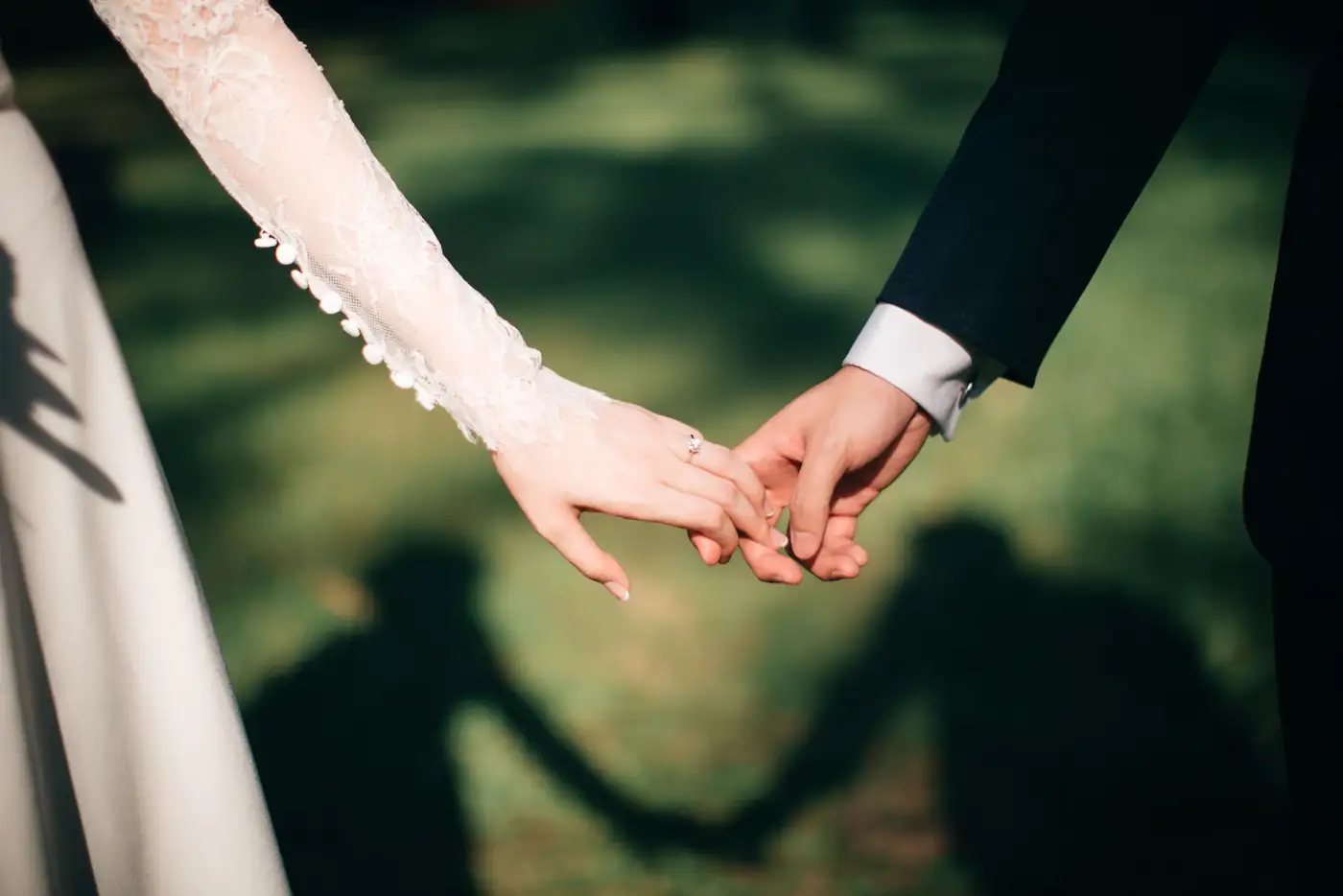 Two hands held, shadows on the grass
