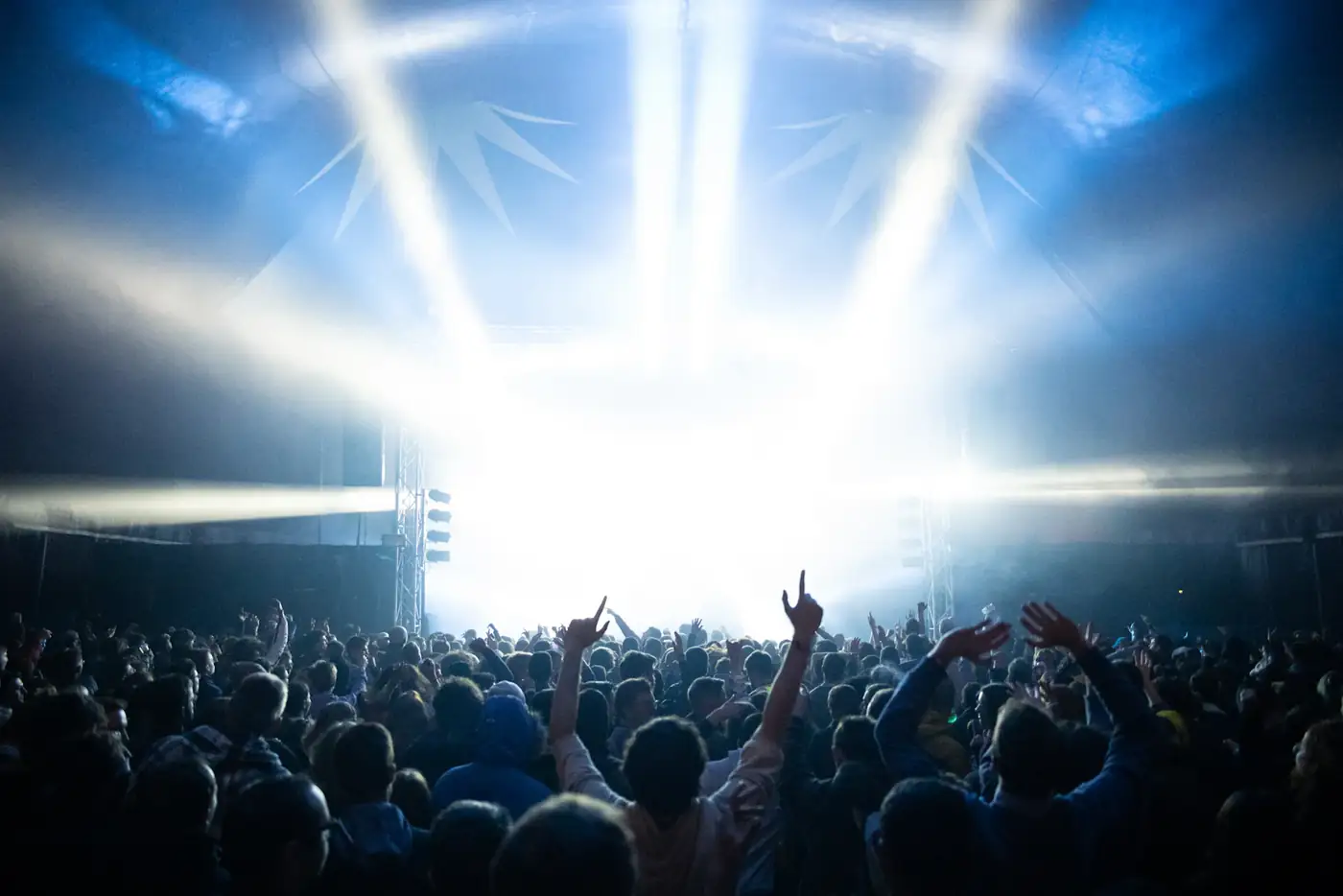 White light blasting over a crowd with raised hands