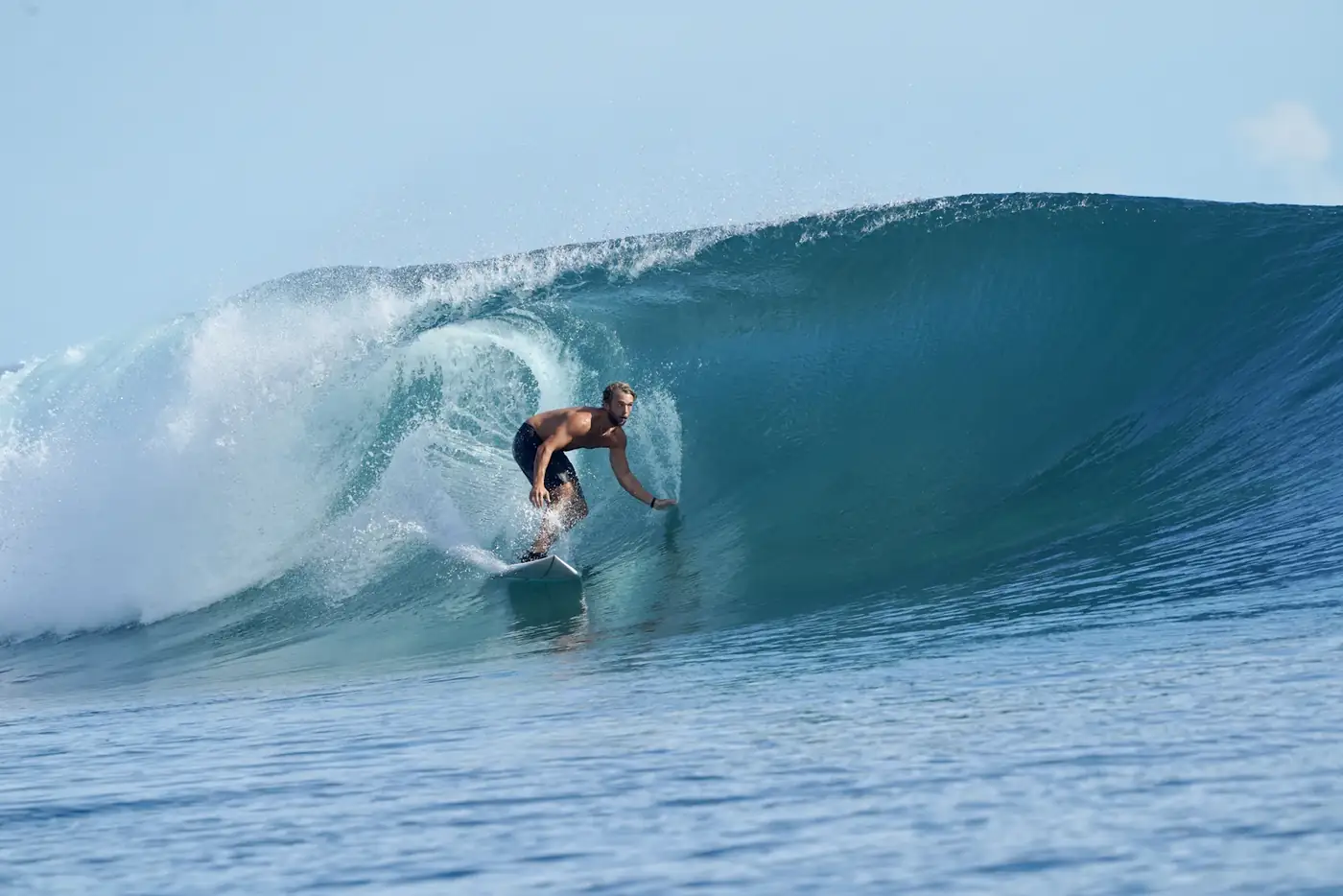 Surfer crouched inside a blue barrel