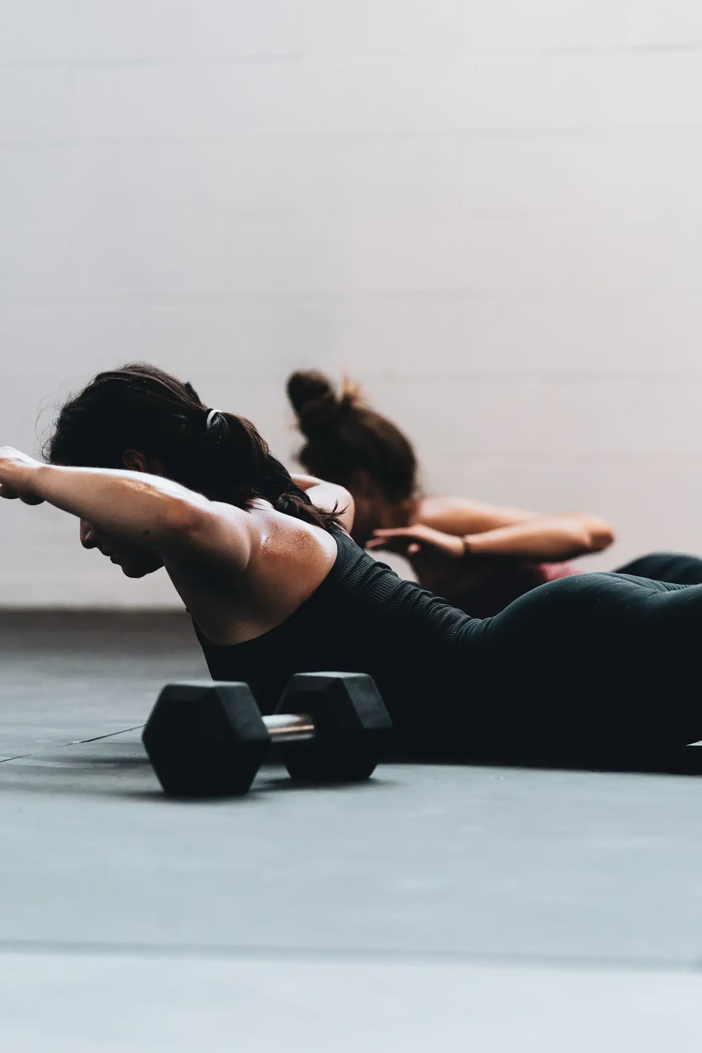 Two women training with dumbbells on the floor