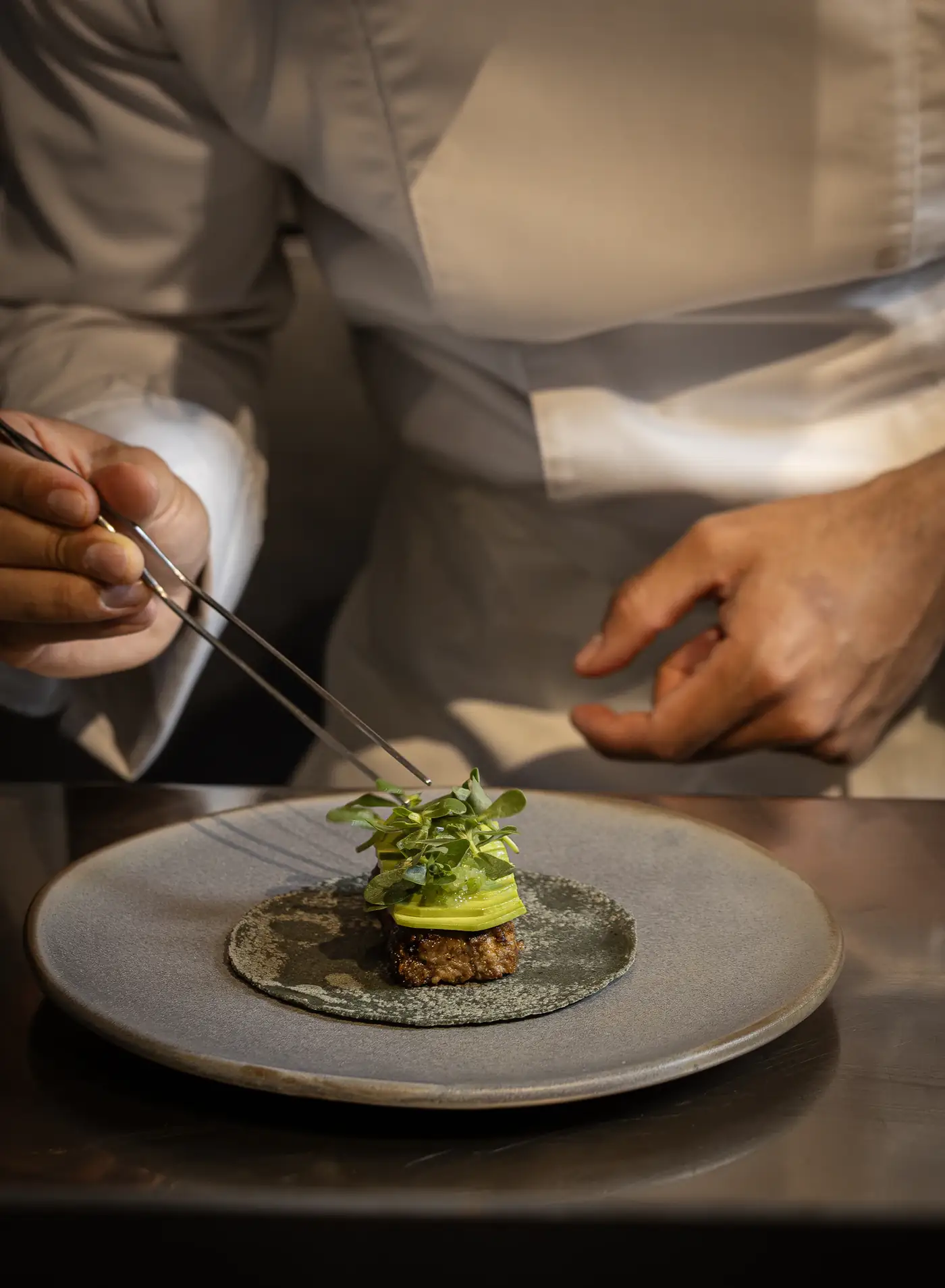 Chef placing herbs on a plate with tweezers