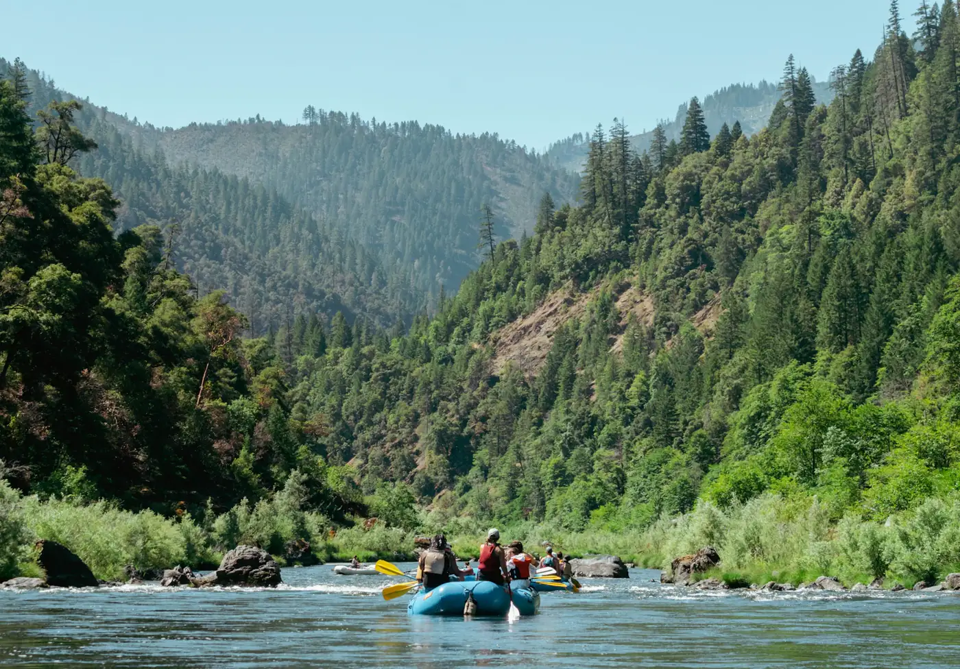 A raft drifting on a calm river through a green valley